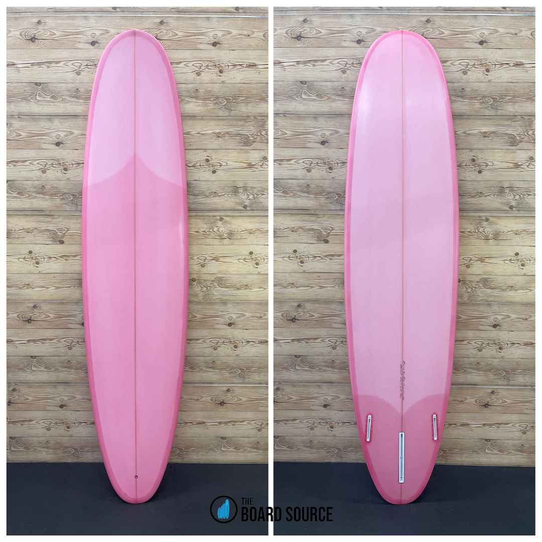 A pink surfboard displayed in two orientations on a wooden background, showing the top and bottom of the board.