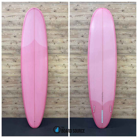A pink surfboard displayed in two orientations on a wooden background, showing the top and bottom of the board.