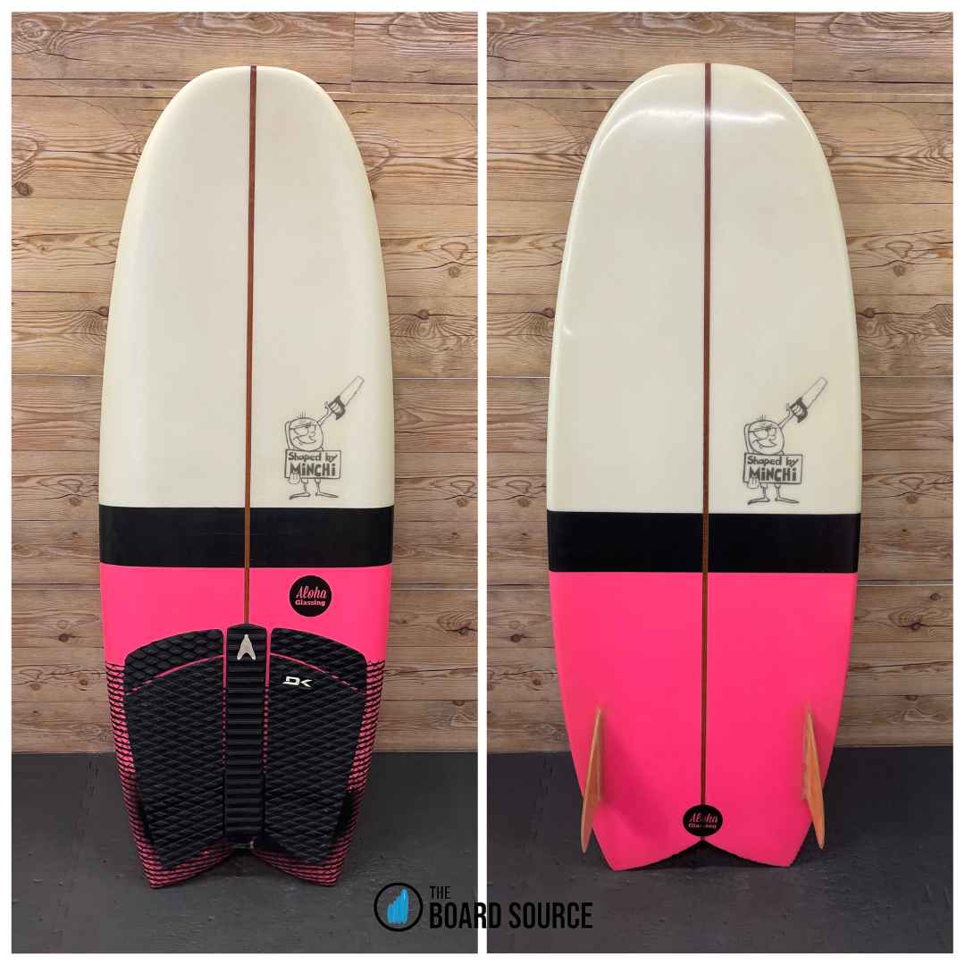 A used Simms fish surfboard with a pink and white color scheme, shown from the top and bottom views, featuring a logo and black traction pads.